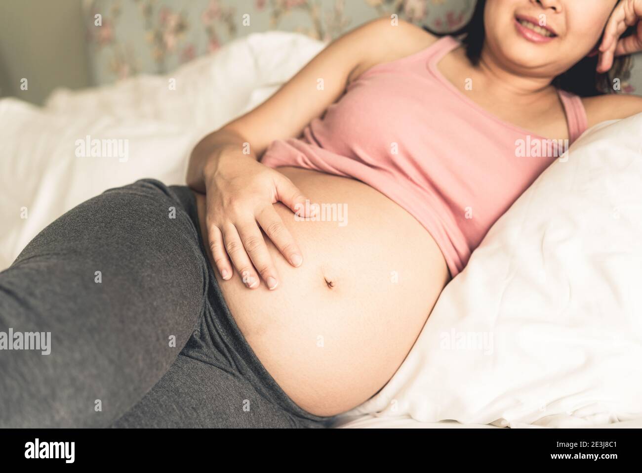 Femme enceinte se sentant heureuse à la maison tout en prenant soin de son enfant. Le jeune s'attend à ce que la mère tient bébé dans le ventre de la grossesse. Maternité prénatale Banque D'Images