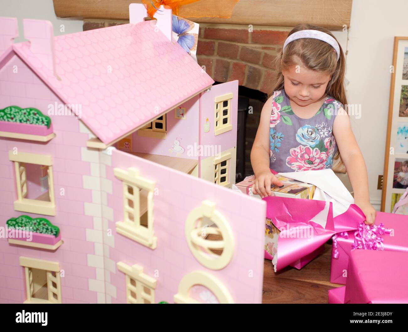 Une fille de quatre ans ouvre ses cadeaux d'anniversaire Banque D'Images