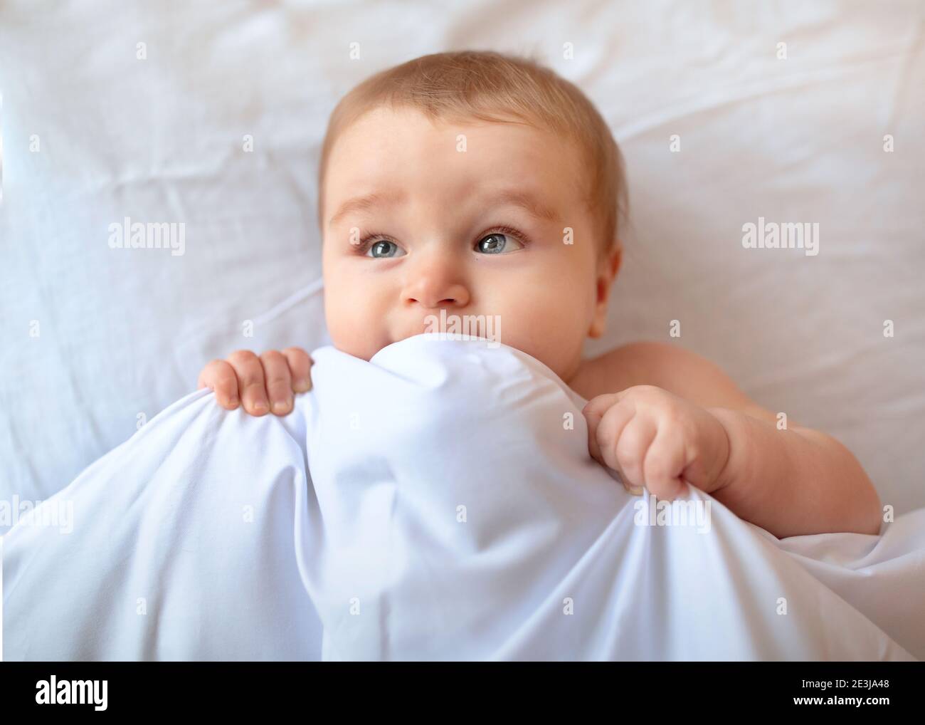 Adorable bébé sous une couverture dans le lit, gros plan Banque D'Images