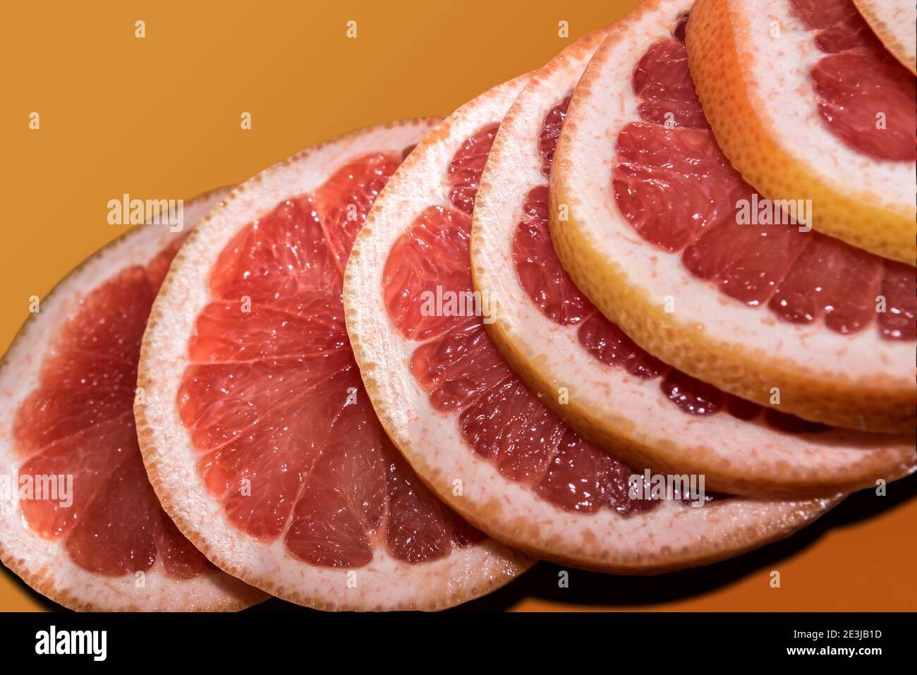Des tranches d'oranges rouges de Sicile empilées sur fond orange Banque D'Images Des tranches d'oranges rouges de Sicile empilées sur fond orange Banque D'Images