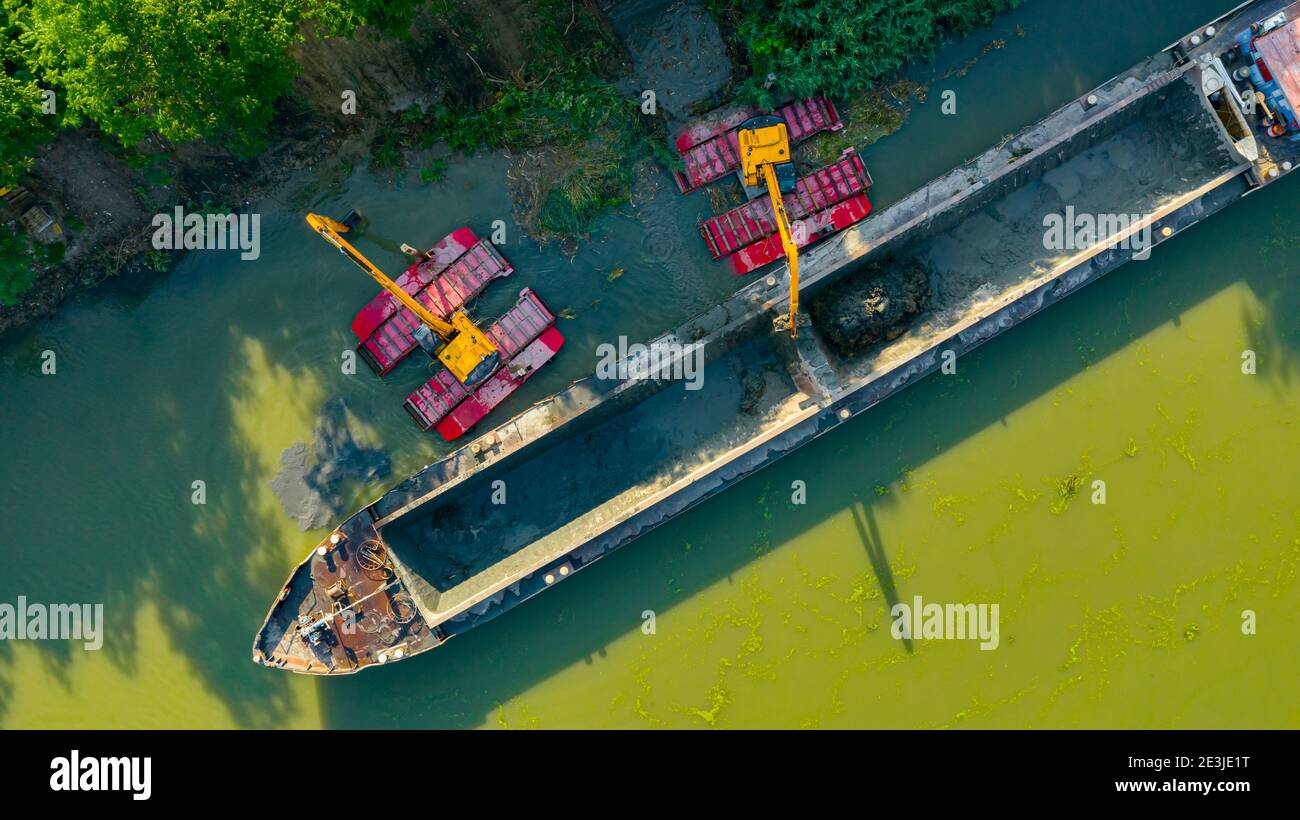 Au-dessus de la vue de dessus sur deux excavatrices drague comme ils dragage, travaillant sur la rivière, canal, l'approfondissement et l'enlèvement des sédiments, la boue du lit de rivière dans un pollué Banque D'Images