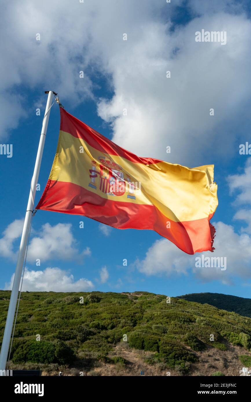 Drapeau national espagnol volant dans le vent contre un bleu ciel Banque D'Images
