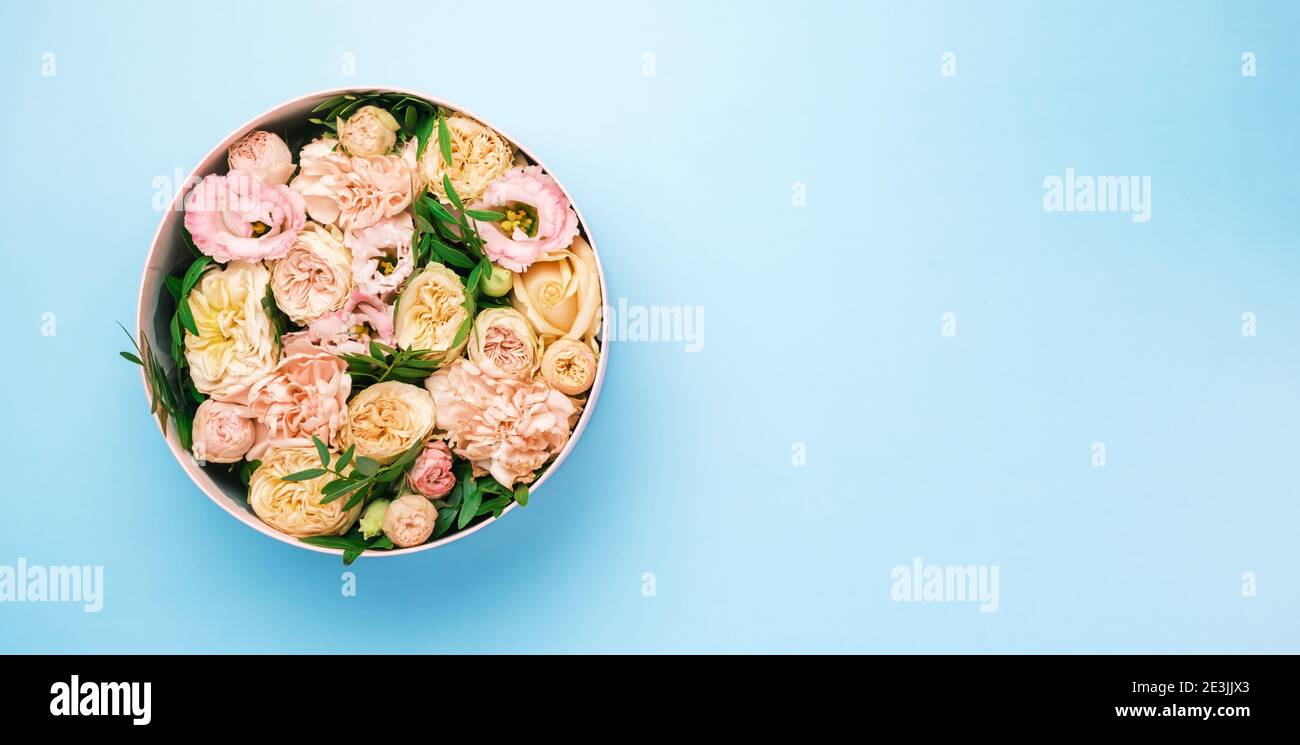 Une fleur élégante et délicate dans une boîte ronde à chapeau sur fond rose avec espace de copie. Boîte cadeau pour le 8 mars, Journée internationale de la femme Banque D'Images