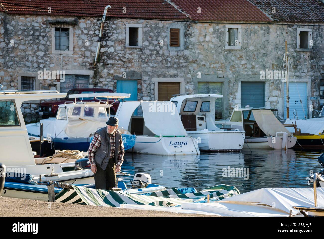 Homme dans son bateau, Port au Mali Iz, sland d'Iz, archipel de Zadar, Dalmatie, Croatie Banque D'Images