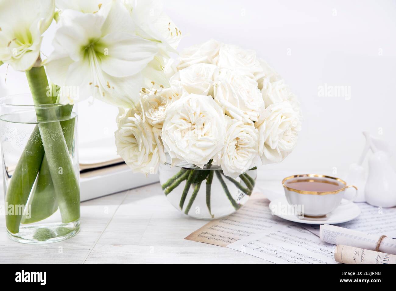 Roses blanches, nénuphars, dans des vases ronds avec deux tasses de café sur la table pour une occasion spéciale comme décoration de cuisine. Copier l'espace Banque D'Images