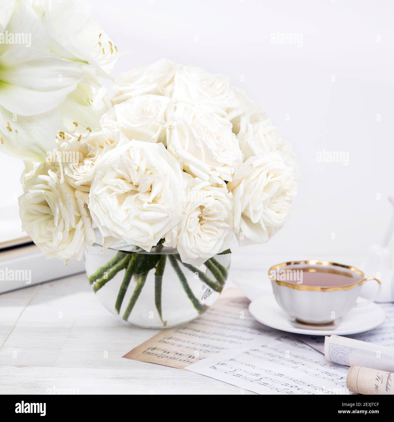 Roses blanches, nénuphars, dans des vases ronds avec deux tasses de café sur la table pour une occasion spéciale comme décoration de cuisine. Copier l'espace Banque D'Images