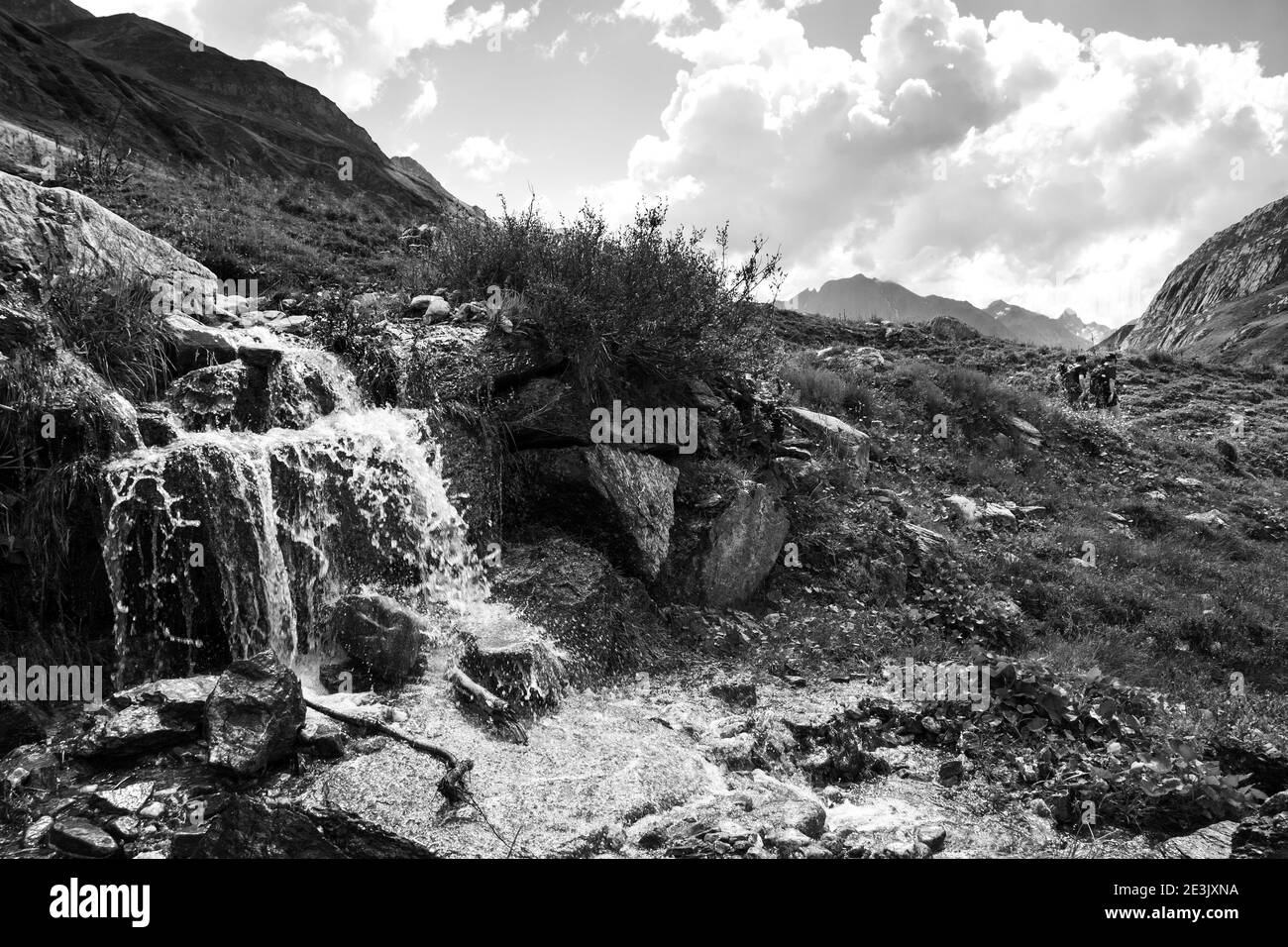 Deux amis (hommes méconnaissables; vue arrière) randonnée dans les montagnes des Alpes françaises en été en passant près de la cascade. Vue depuis la vallée de Chapieux, Savoie, Franc Banque D'Images