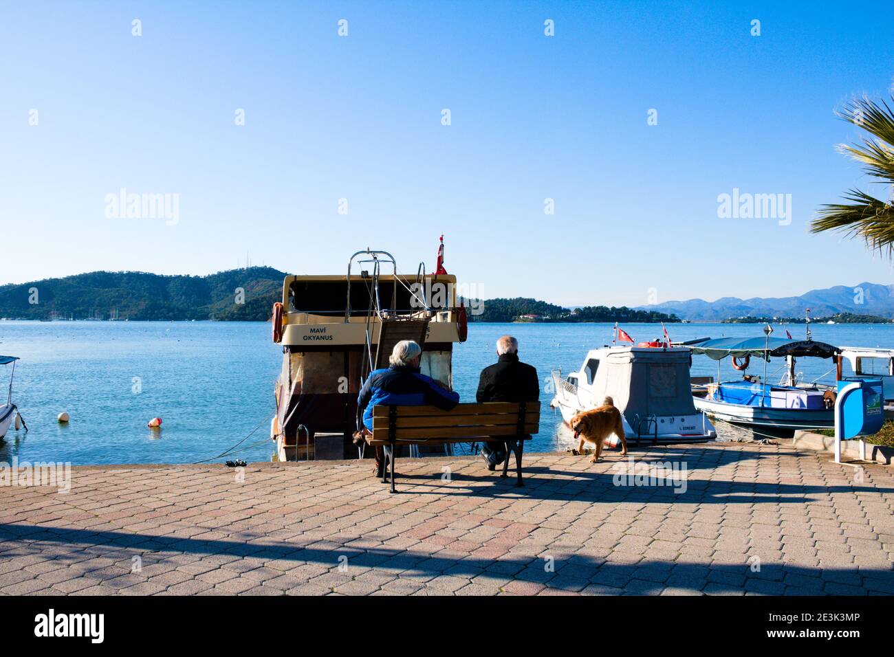 Deux personnes âgées assises sur le banc de la côte. Ciel bleu et plage. Banque D'Images