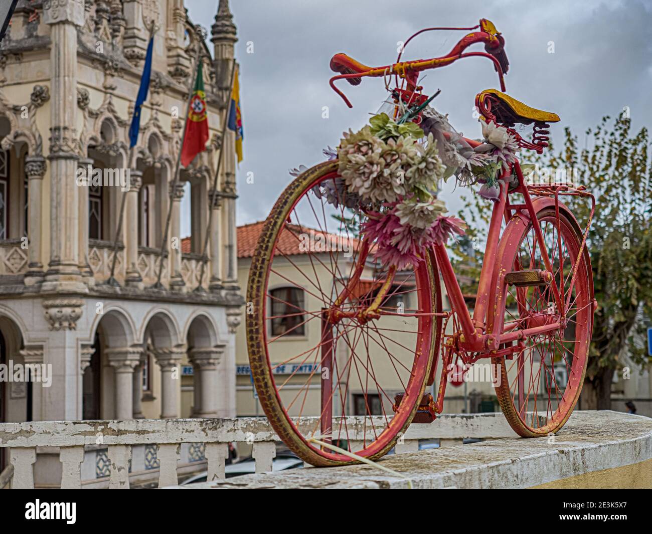 Vieux vélo rouge sur la clôture et un bel hôtel de ville avec les drapeaux de l'Europe, du Portugal et de Sintra en arrière-plan (Câmara Municipal de Sin Banque D'Images