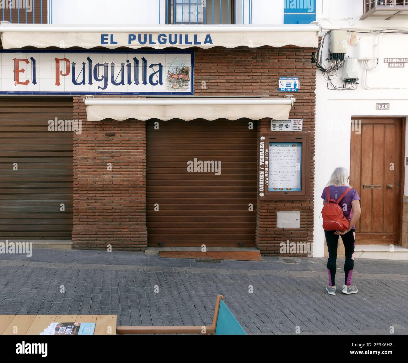 Une touriste femelle part après avoir lu un panneau devant un bar à tapas qui annonce sa fermeture en raison de la situation Covid, Nerja, Malaga, Espagne Banque D'Images