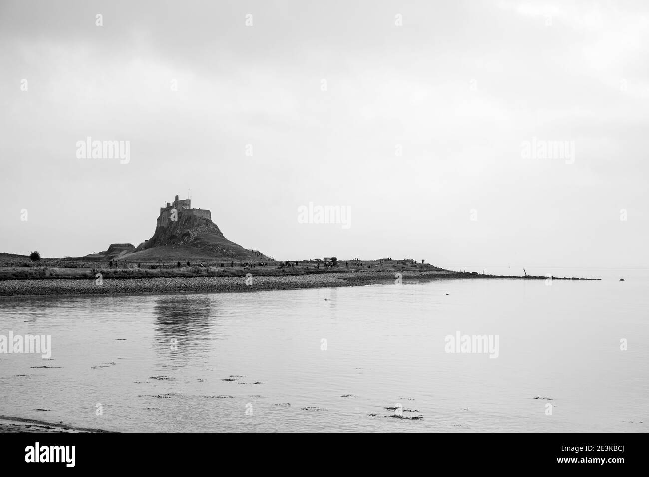 Lindisfarne/Angleterre: 10 sept 2019: Château de l'île Sainte vue de la côte avec marée dans le ciel bleu Banque D'Images