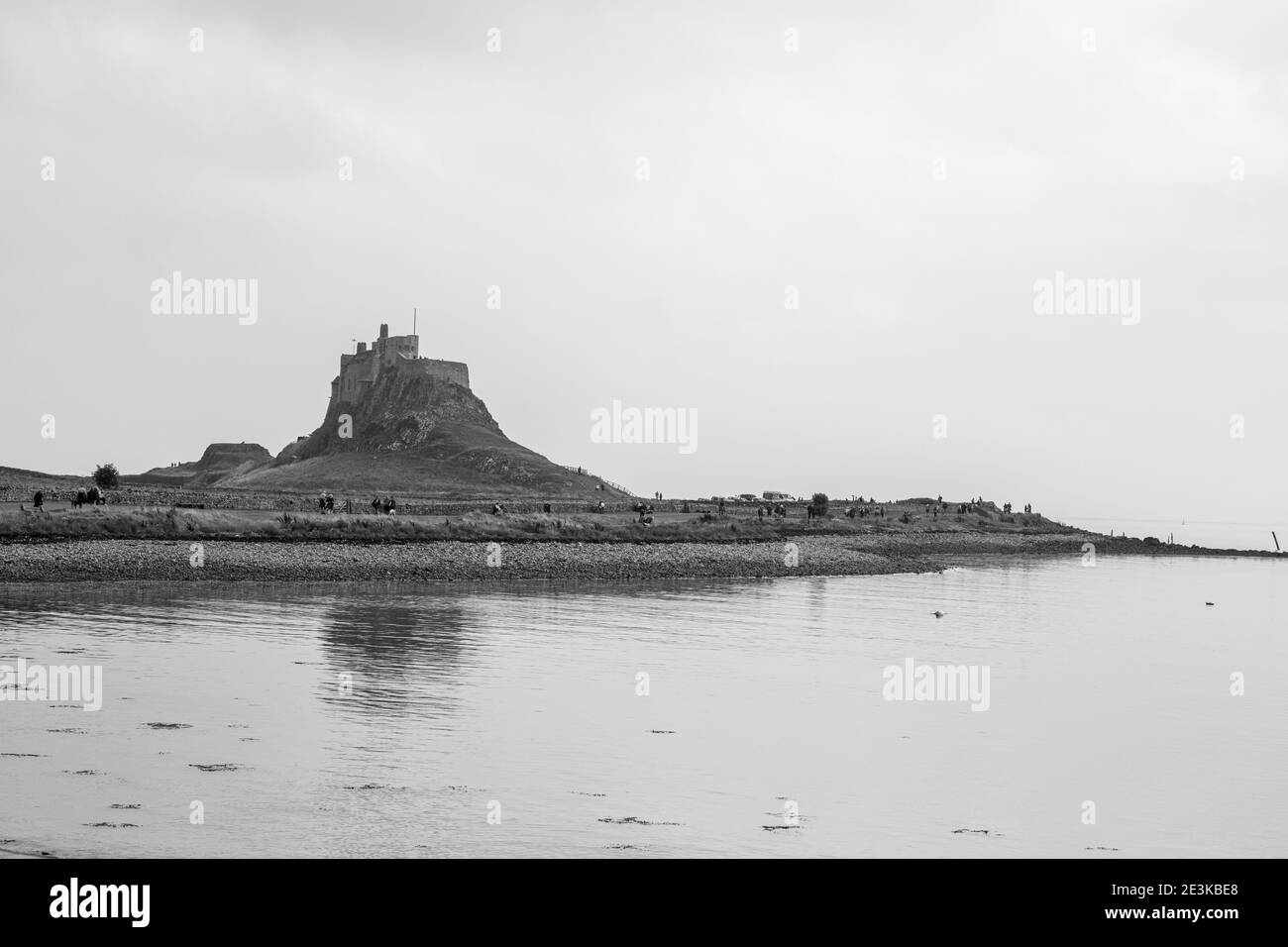 Lindisfarne/Angleterre: 10 sept 2019: Château de l'île Sainte vue de la côte avec marée dans le ciel bleu Banque D'Images