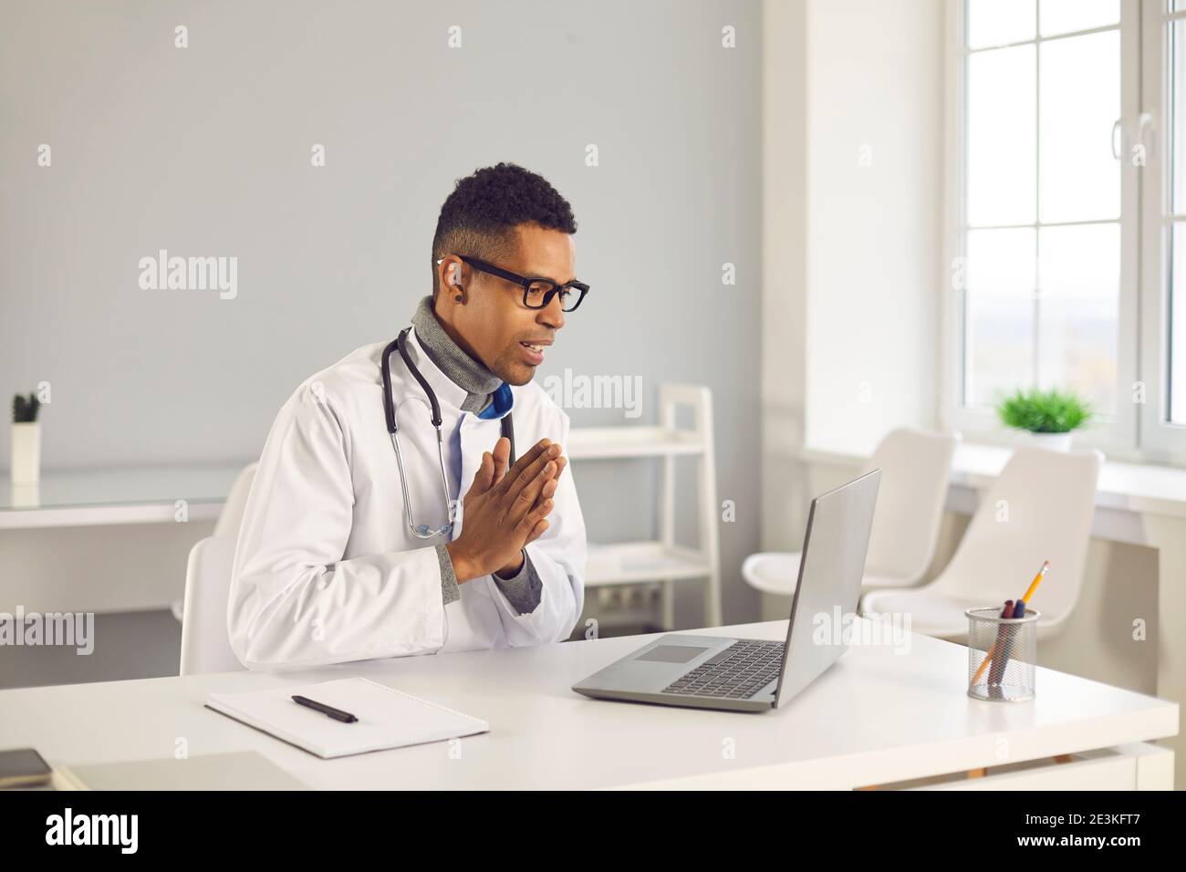 Joyeux médecin en ligne remerciant ou saluant poliment son patient dans réunion virtuelle Banque D'Images