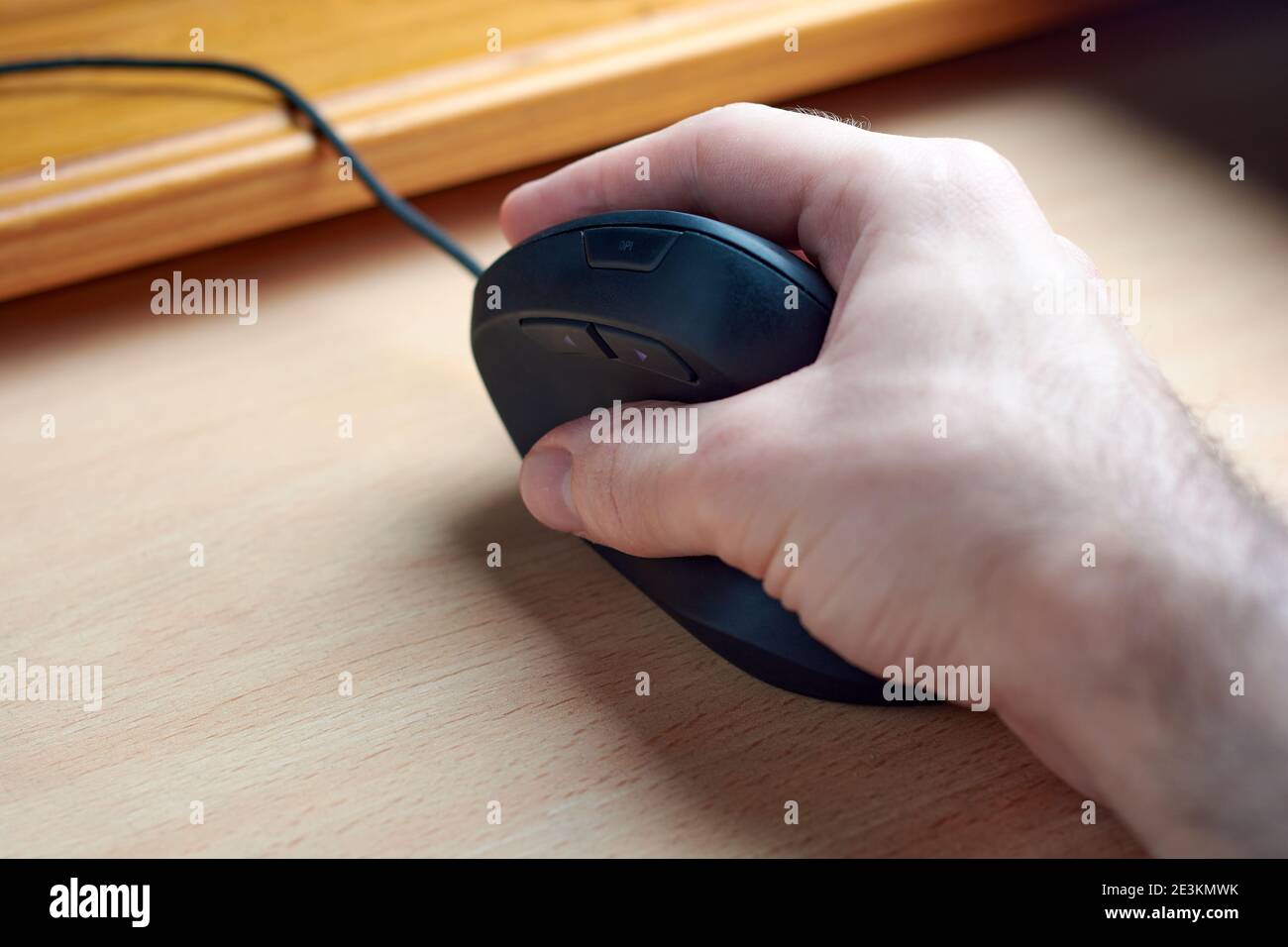 Jeune homme allongé sur une souris verticale de gamer ergonomique pour ordinateur vu d'en haut. Souris qui aide à prévenir des maladies comme le syndrome du canal carpien Banque D'Images
