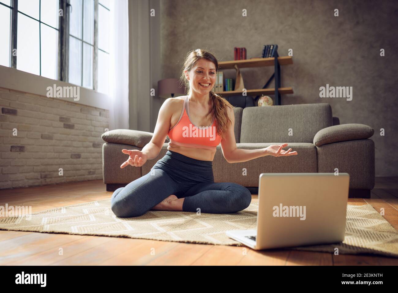 Une jeune femme suit avec un ordinateur portable un exercice de gym. Elle est à la maison en raison de la quarantaine du coronavirus codiv-19 Banque D'Images