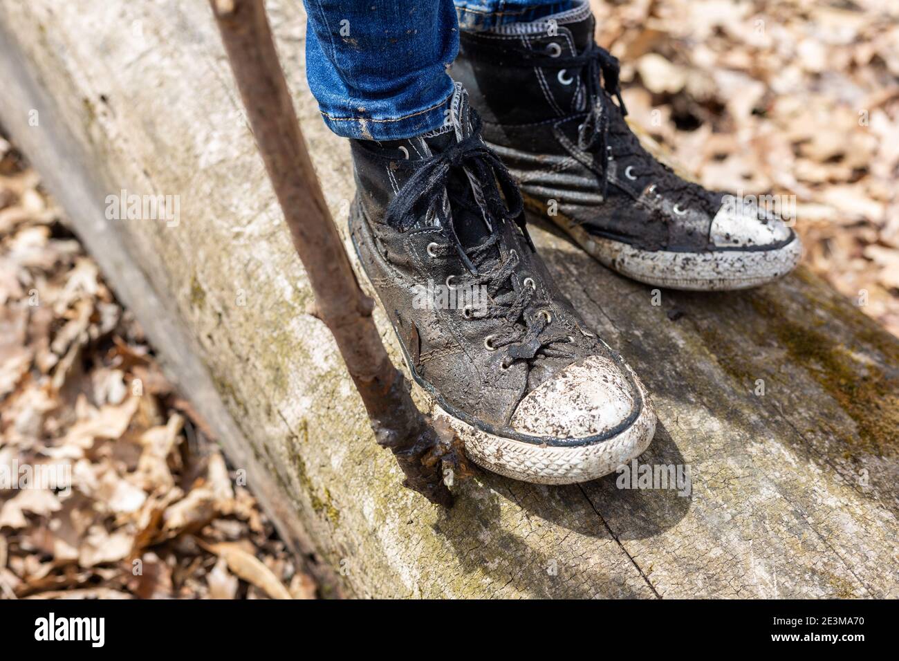 Une jeune fille porte des chaussures boueuses lorsqu'elle marche sur une bûche à Mengerson Park à fort Wayne, Indiana, États-Unis. Banque D'Images