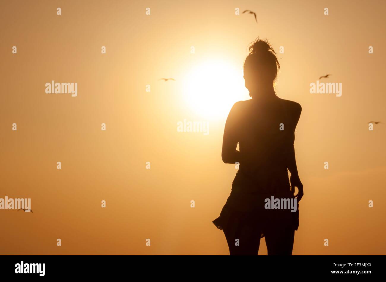 Silhouette jeune femme appréciant sur la plage avec un coucher de soleil. Personne insouciante appréciant en vacances Banque D'Images