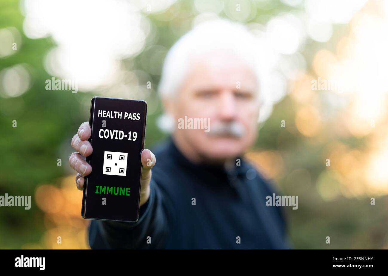 Homme âgé présentant un certificat de vaccination sur un téléphone portable, qui indique une vaccination contre le covid-19. Banque D'Images