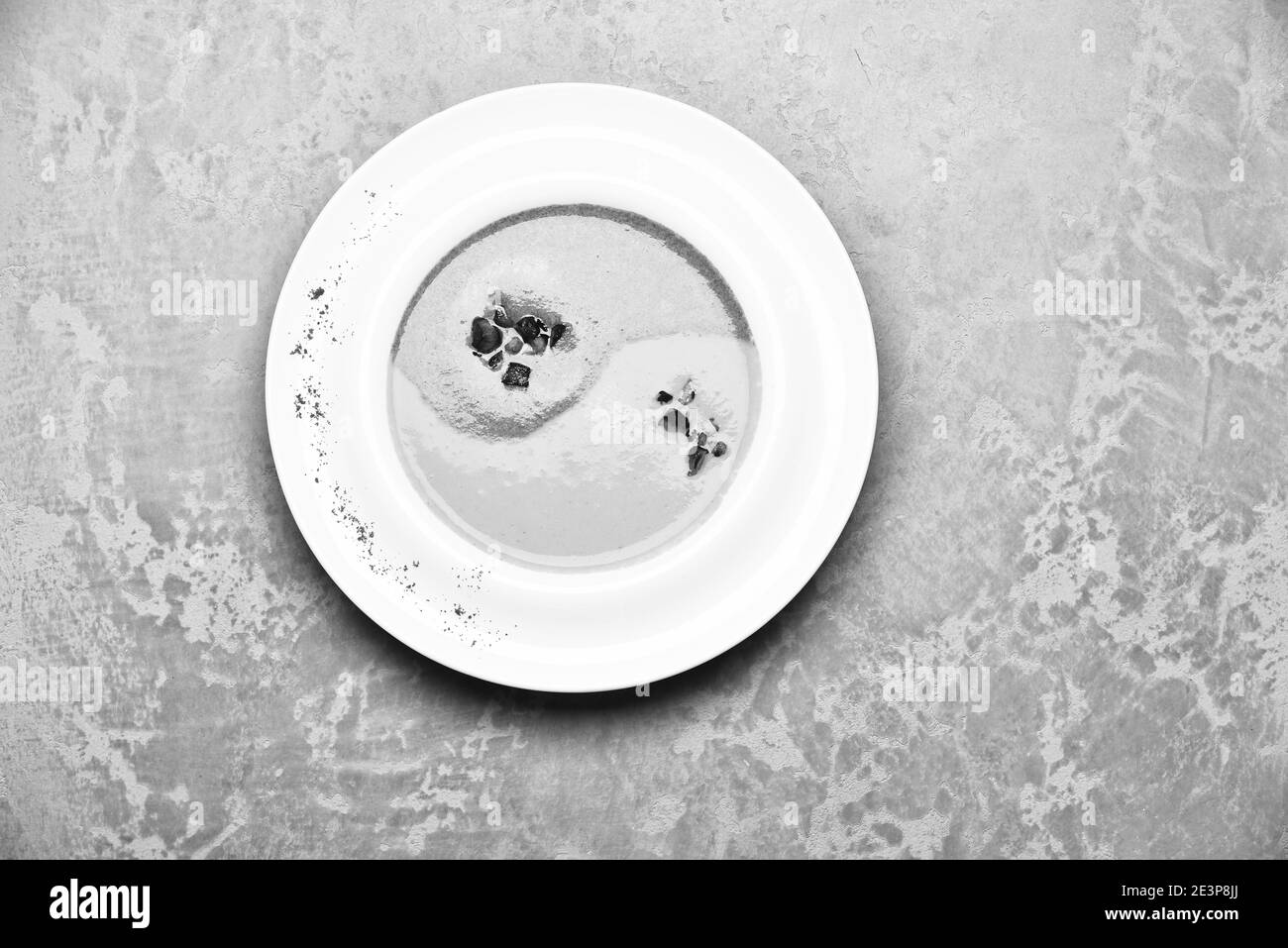 Concept de cuisine traditionnelle. Soupe à la crème d'épinards et de potiron sur fond de texture grise. Purée de couleur verte et jaune dans le yin yang signe avec morceaux de bacon dans la plaque blanche. Décor de soupes japonaises. Banque D'Images