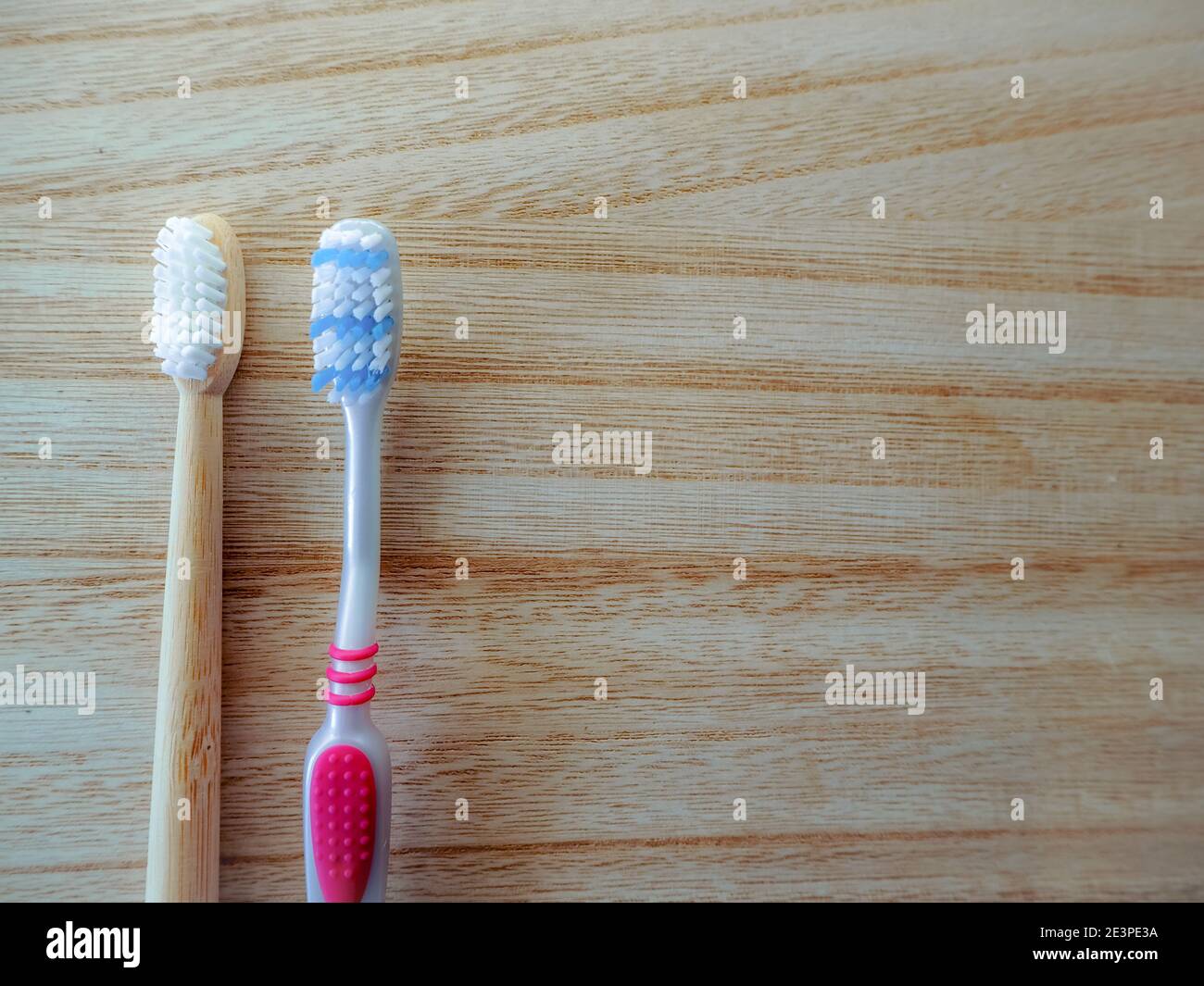 Concept de remplacement de style de vie sans plastique avec brosse à dents en plastique et brosse à dents en bambou comme alternative durable sur fond de bois. Banque D'Images
