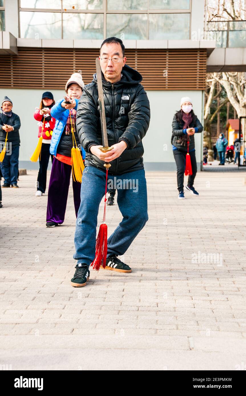 Les gens qui pratiquent le tai chi au sabre dans le parc Fuxing de Shanghai par un hiver froid. Banque D'Images