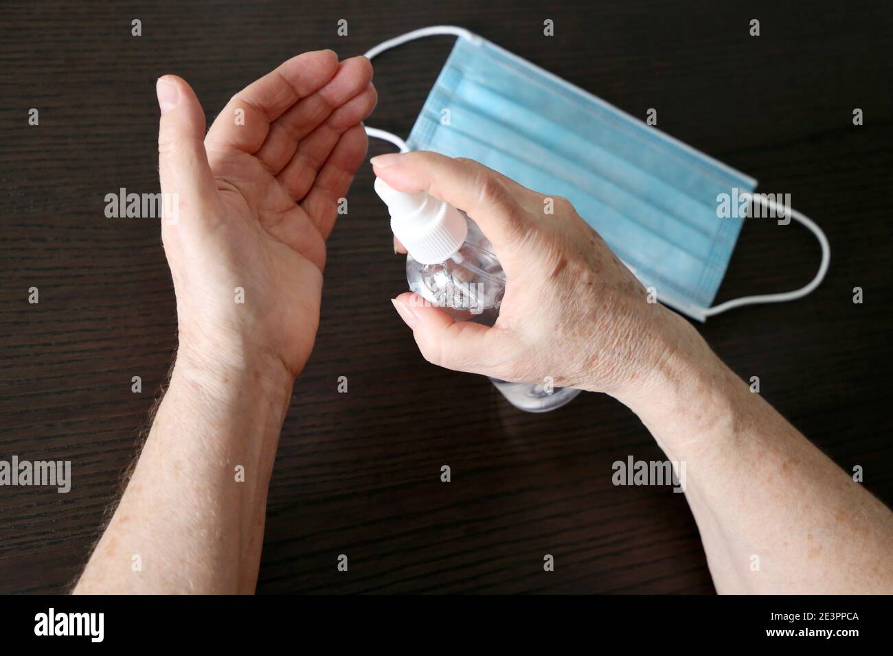 Femme âgée désinfectant la peau de ses bras, prévention de l'infection du coronavirus. Mains et bouteille de femme avec vaporisateur d'assainisseur Banque D'Images