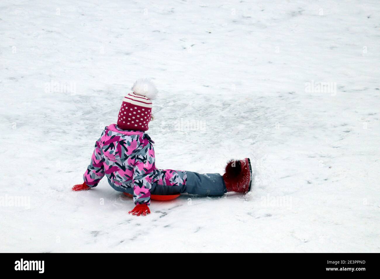 Enfant sur un plateau, traîneau d'hiver. Petite fille qui descend la colline de la neige Banque D'Images