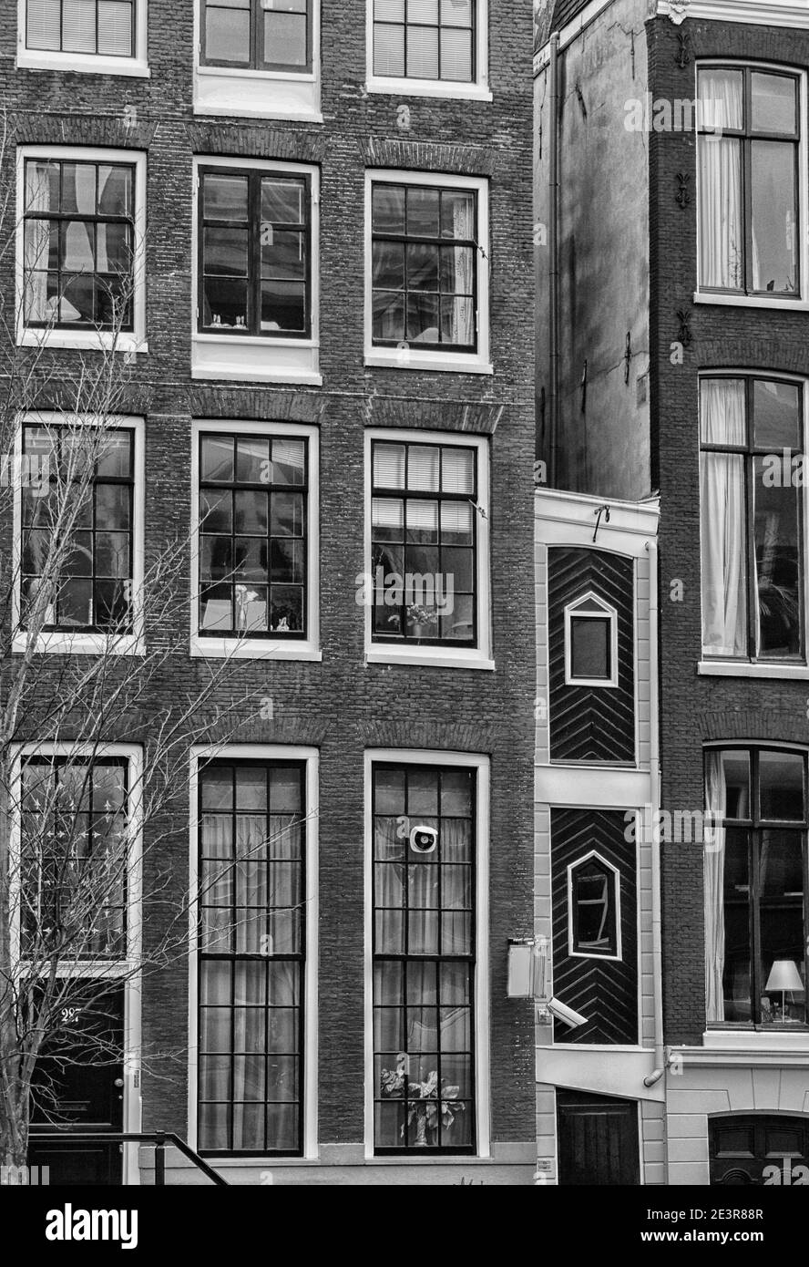 Un mètre (3.3 pi) grande maison entre deux maisons beaucoup plus grandes sur un canal À Amsterdam en noir et blanc Banque D'Images