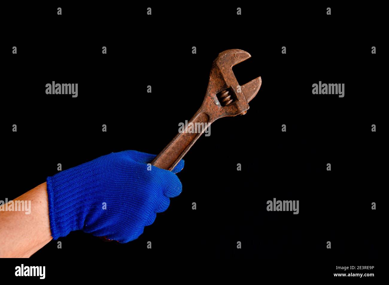 La main d'un homme dans un gant bleu tient une clé rouillée. Gros plan Banque D'Images
