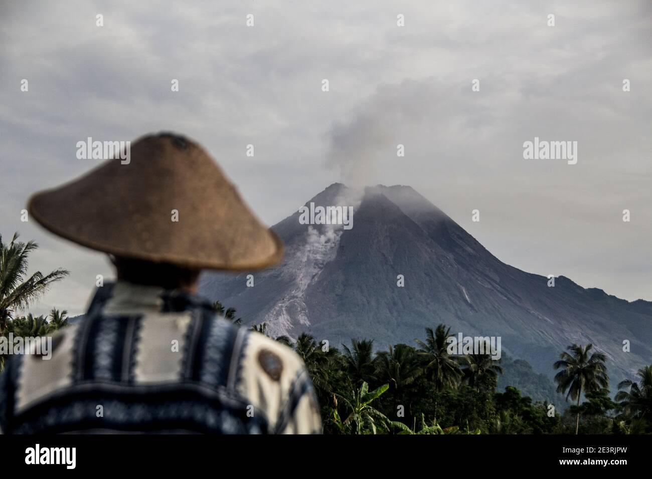 Sleman, YOGYAKARTA, INDONÉSIE. 20 janvier 2021. Les agriculteurs observent le Mont Merapi, qui émet de la fumée qui s'élève au-dessus de son sommet, vu à Sleman, Yogyakarta, Indonésie, le mardi 20 janvier 2021. Le chef de l'Agence de recherche et de développement en cas de catastrophe géologique (BPPTKG), Hanik Humaida, a déclaré que le Mont Merapi avait éclaté huit fois avec une distance de glissement maximale de 1,500 mètres au sud-ouest. Nuage chaud d'avalanche d'amplitude maximale de 30 mm, durée maximale de 192 secondes. Credit: Slamet Riyadi/ZUMA Wire/Alamy Live News Banque D'Images