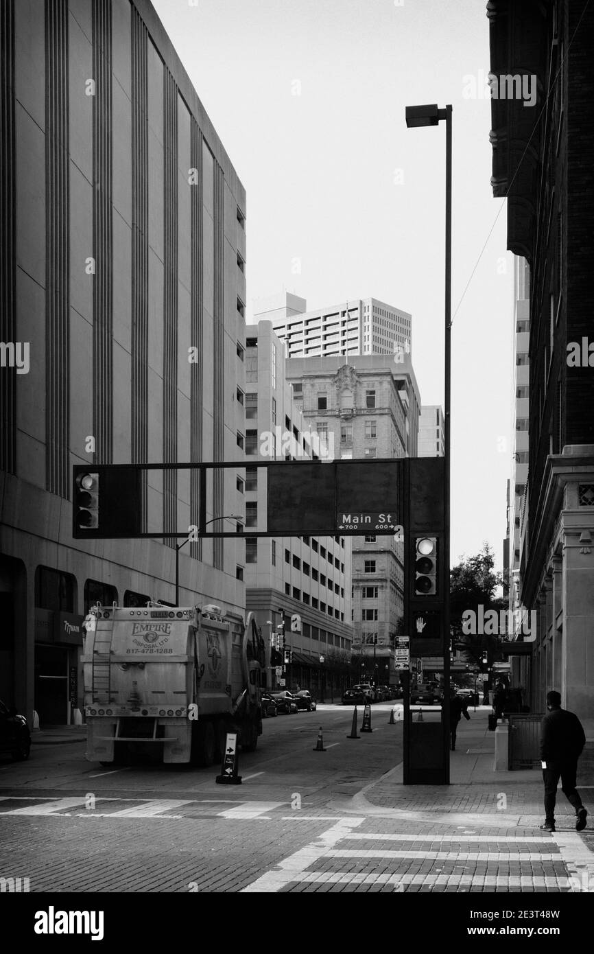 Scène de rue depuis le centre-ville de fort Worth avec camion de déchets entre de grands bâtiments à une intersection en noir et blanc Banque D'Images