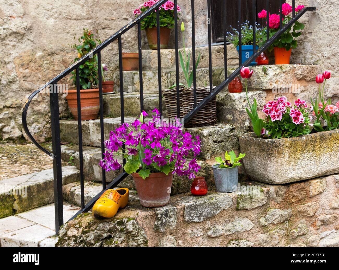Ancienne maison en pierre entrée avec des pots de fleurs colorés sur la rue étroite dans le village médiéval français, Nouvelle-Aquitaine, France Banque D'Images