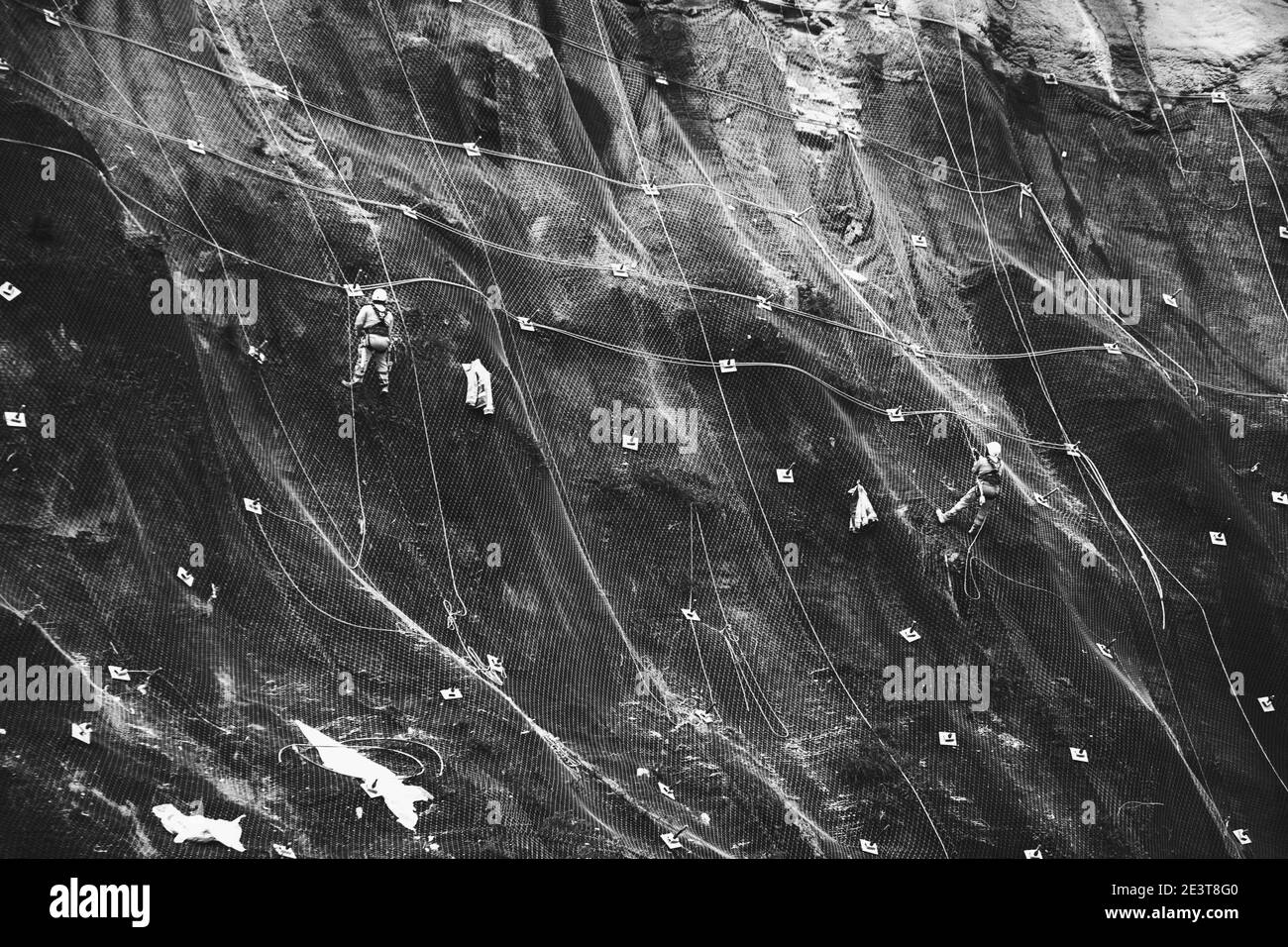 Les travailleurs renforcent la pente de la montagne avec un maillage métallique empêchant la chute sur la route. Hondarribia, Espagne. Résumé du concept de sécurité Banque D'Images