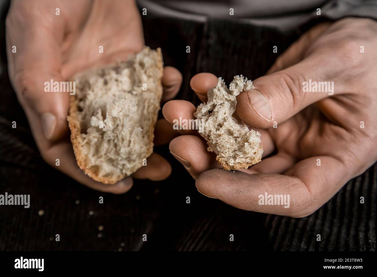 Les mains du pauvre tiennent des morceaux de pain. La faim et la pauvreté. Banque D'Images