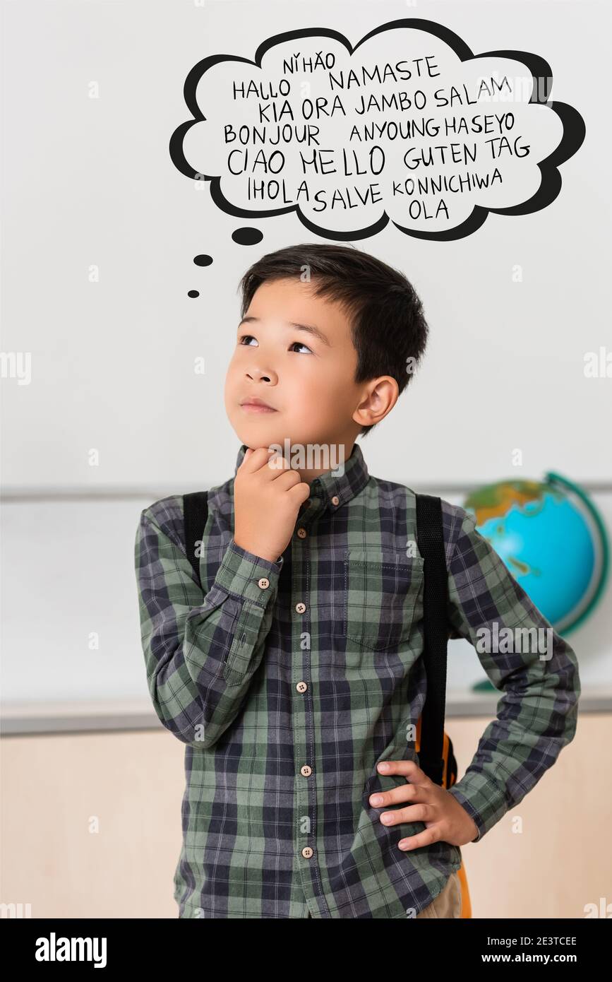 Un écolier asiatique bien pensé, avec la main sur la hanche en classe, a pensé avec bulle de langues Banque D'Images