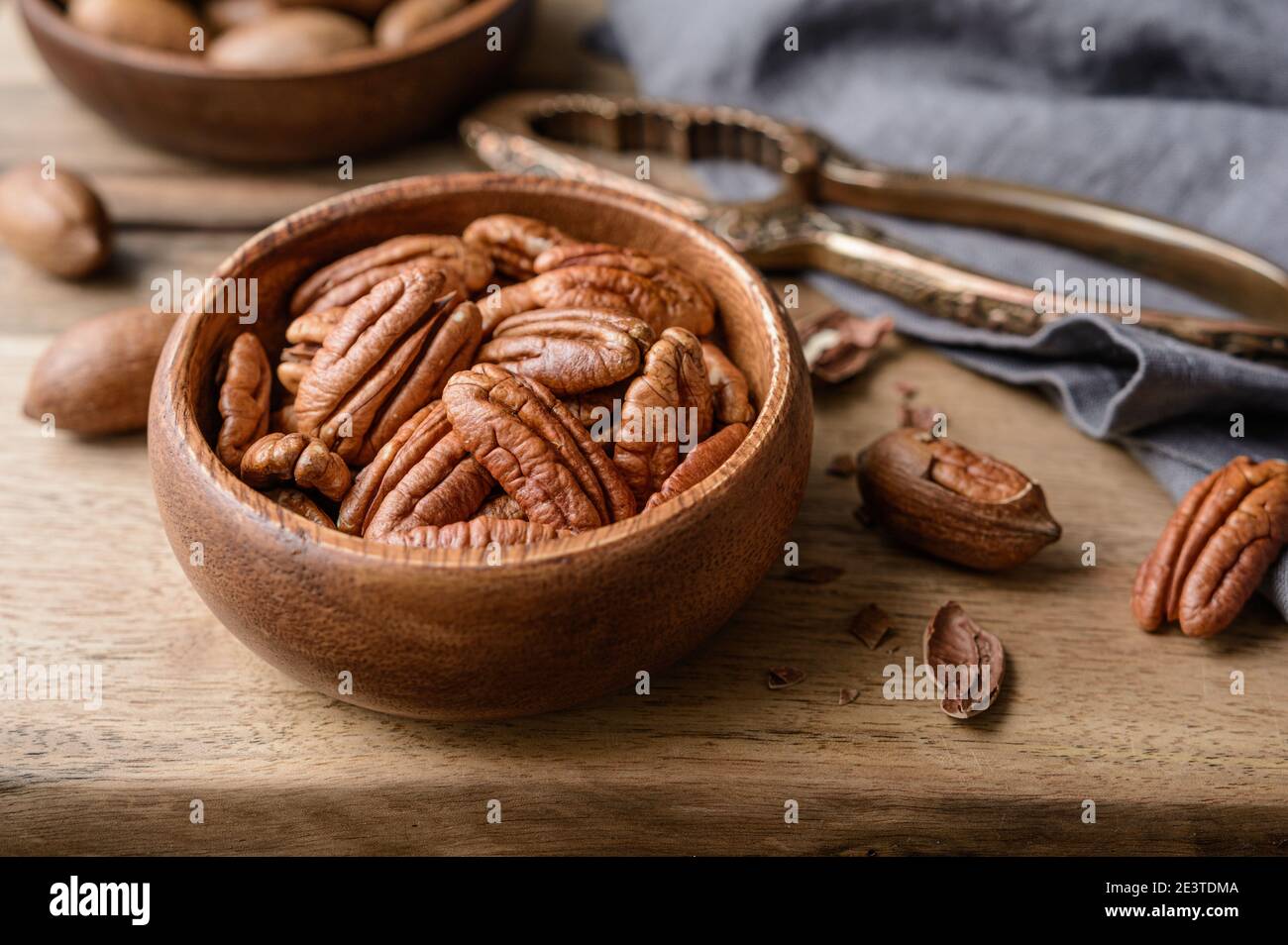 En-cas sain, riche en vitamines et minéraux, pacanes fraîches décortiquées et en coquillages dans un bol sur fond de bois Banque D'Images