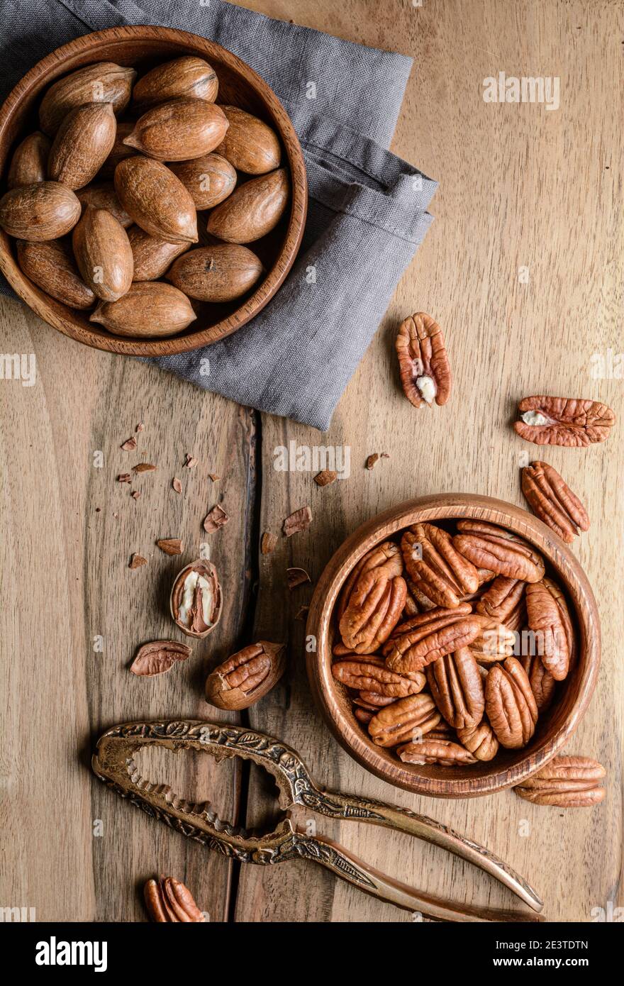 En-cas sain, riche en vitamines et minéraux, pacanes fraîches décortiquées et en coquillages dans un bol sur fond de bois Banque D'Images