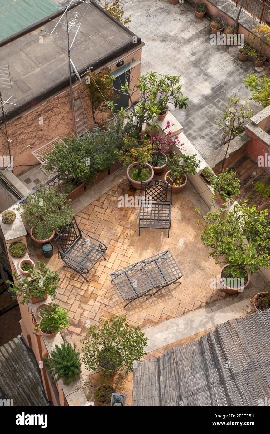 Vue aérienne donnant sur une terrasse sur le toit du jardin à Trastevere, Rome, Italie. Une table et des chaises sur un petit patio, et des plantes dans des conteneurs. Banque D'Images