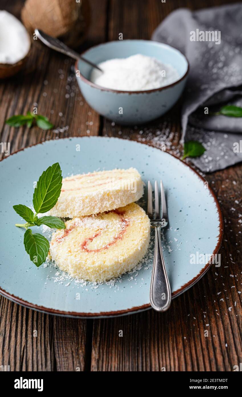 Délicieux dessert, tranches de roulade de noix de coco fourrées de vanille et de crème de beurre de rhum sur fond rustique en bois Banque D'Images