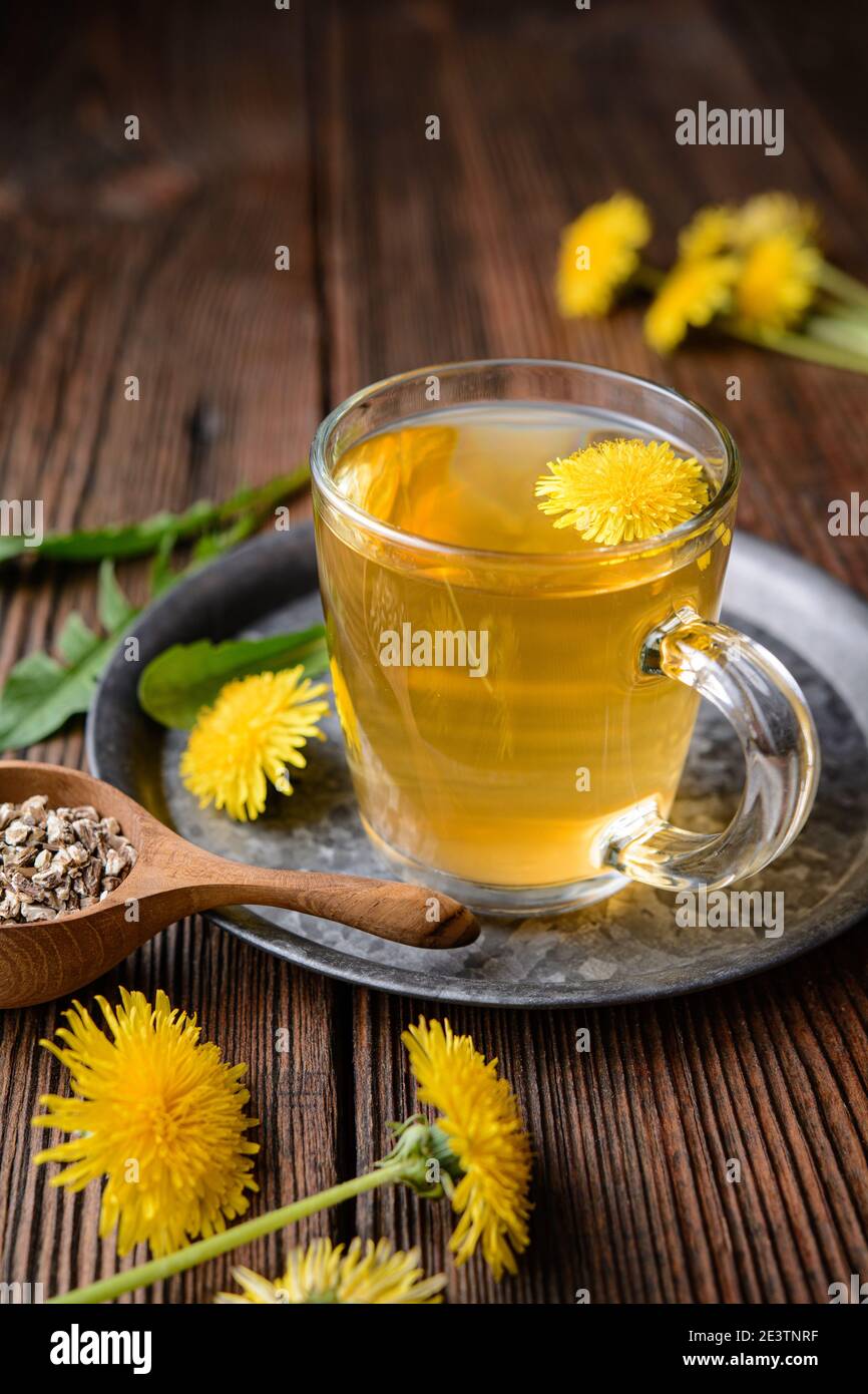 Tisane pour le foie de détox, thé de racine de pissenlit dans une tasse de verre décorée de fleurs fraîches sur un fond rustique en bois Banque D'Images