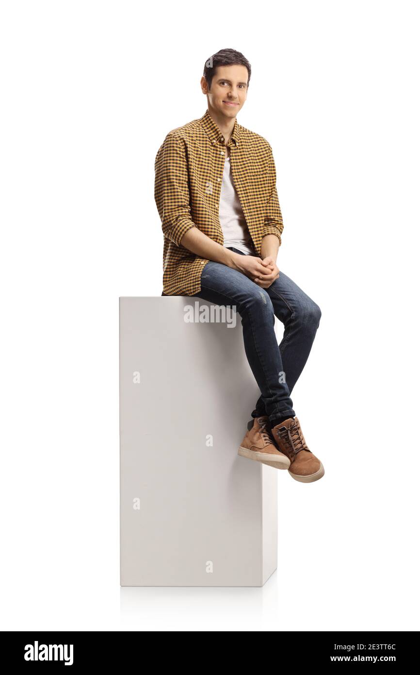 Jeune homme décontracté assis sur une colonne blanche isolée arrière-plan blanc Banque D'Images