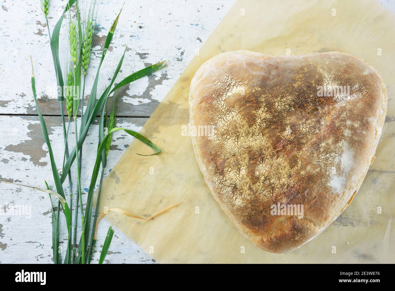 Pain fait maison en forme de coeur et épis de blé vert frais sur une table en bois Banque D'Images