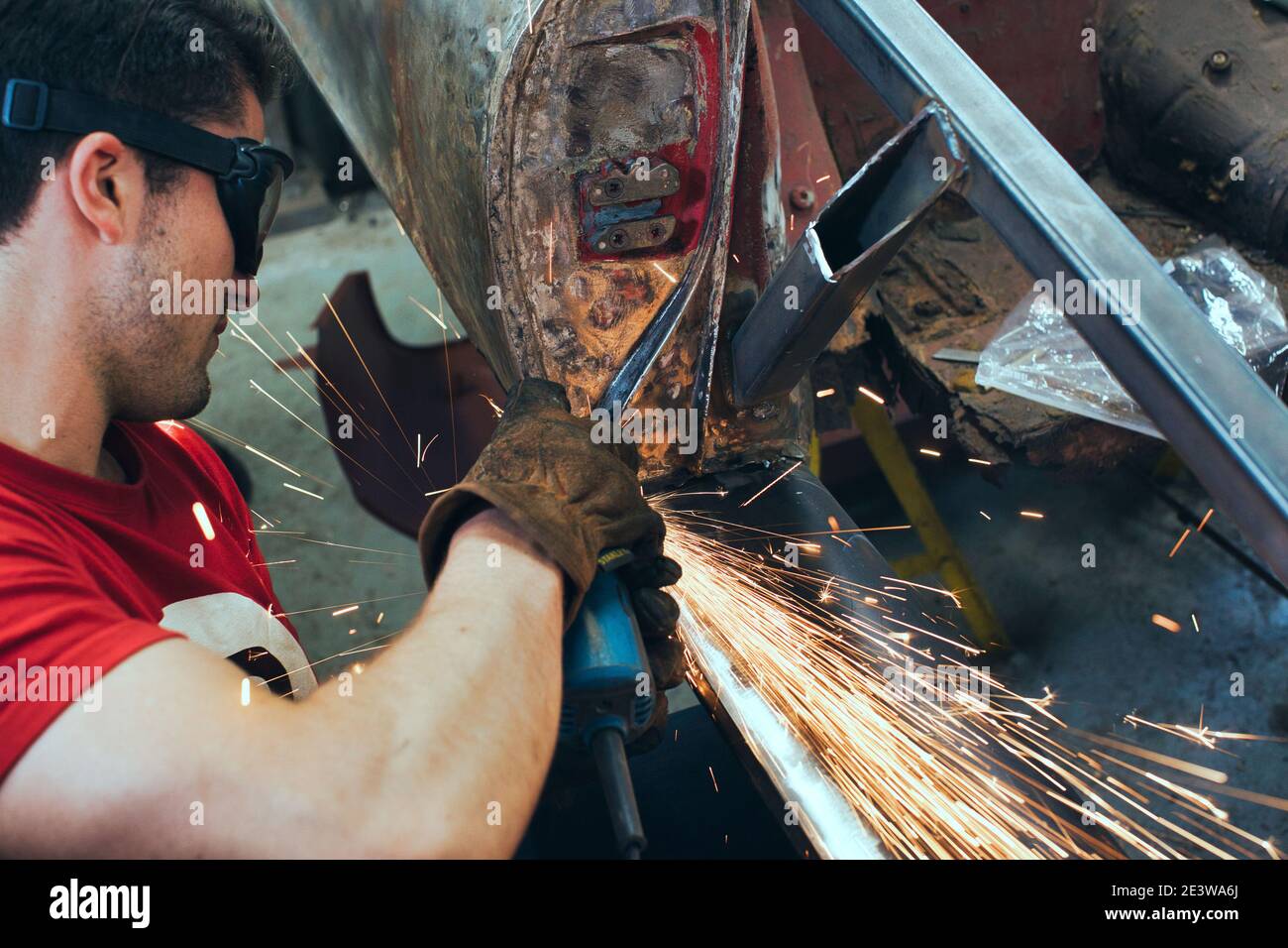 Jeune mécanicien utilisant une meuleuse d'angle dans un atelier automobile Banque D'Images