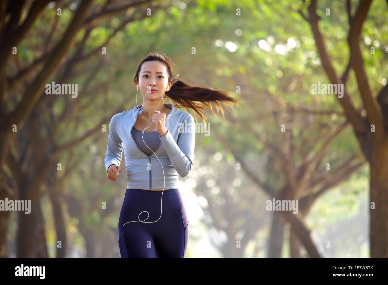 Jeune femme asiatique courant dans la forêt le matin Banque D'Images