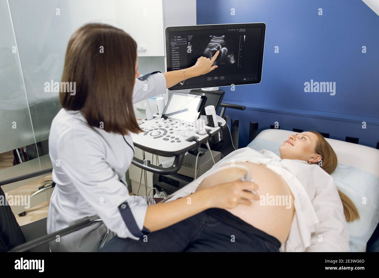 Vue arrière d'une technicienne d'échographie, scanner le ventre d'une femme  enceinte dans une clinique moderne, pointant sur l'écran avec l'image de  bébé Photo Stock - Alamy