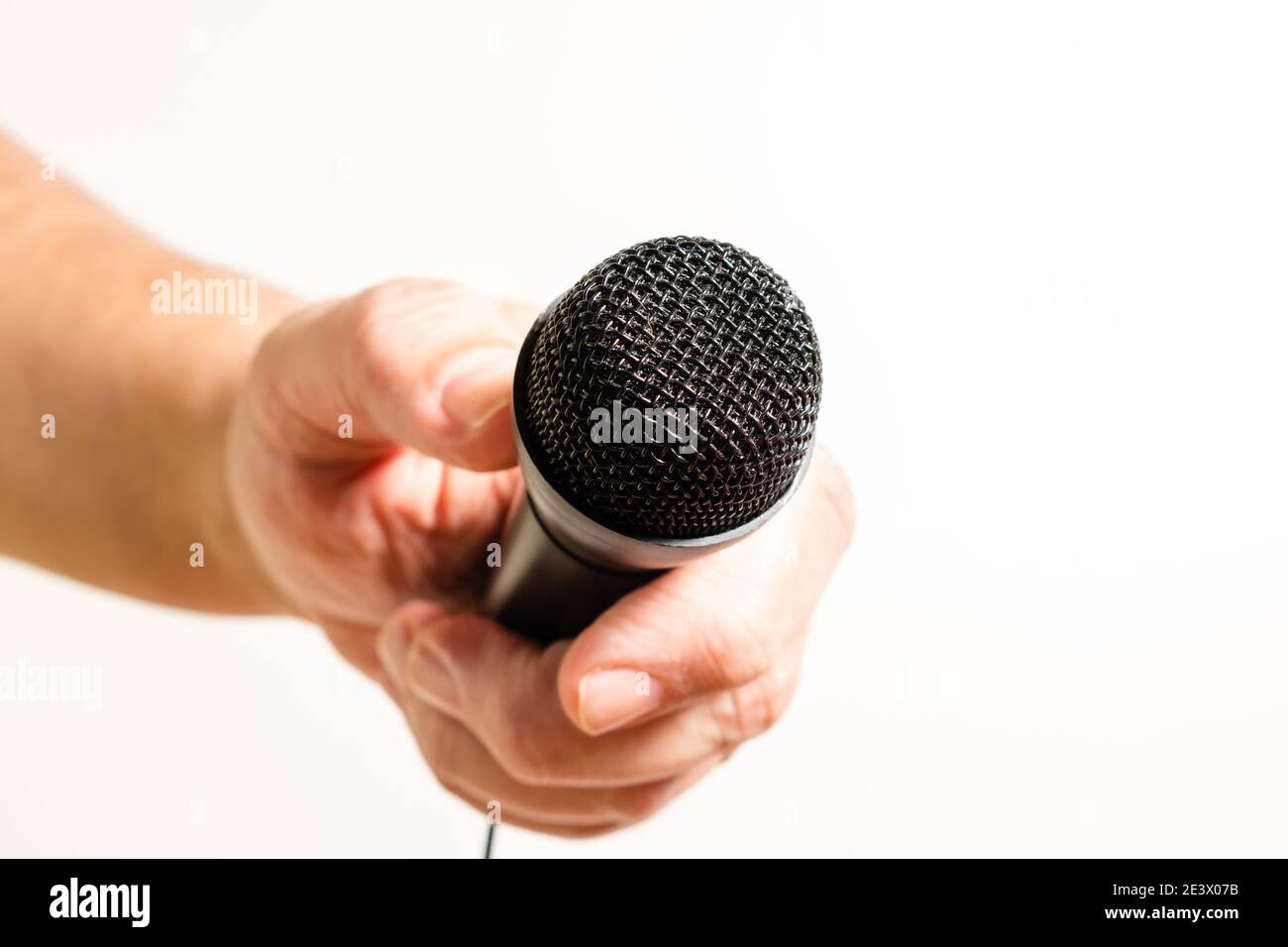 Main d'un homme tenant un microphone noir. Concept de communication, entretiens, dialogues virtuels. Banque D'Images