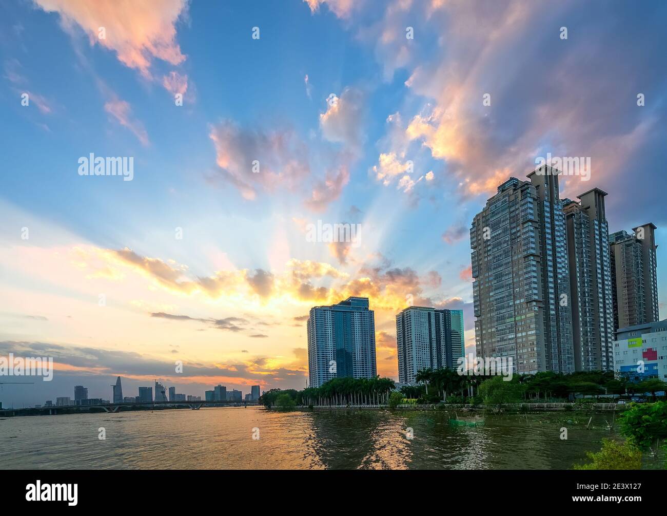 Coucher de soleil dans les zones urbaines le long de la rivière avec des gratte-ciels lire l'éclat par le ciel dramatique créer la beauté du développement urbain à Ho Chi Minh ville, Vietnam Banque D'Images