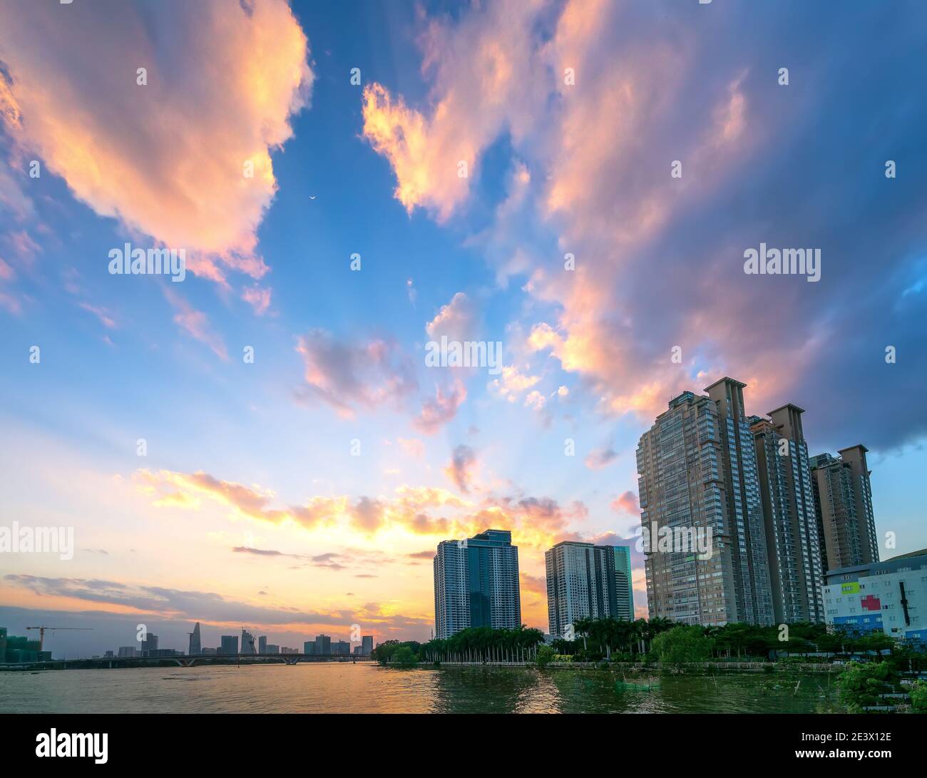 Coucher de soleil dans les zones urbaines le long de la rivière avec des gratte-ciels lire l'éclat par le ciel dramatique créer la beauté du développement urbain à Ho Chi Minh ville, Vietnam Banque D'Images