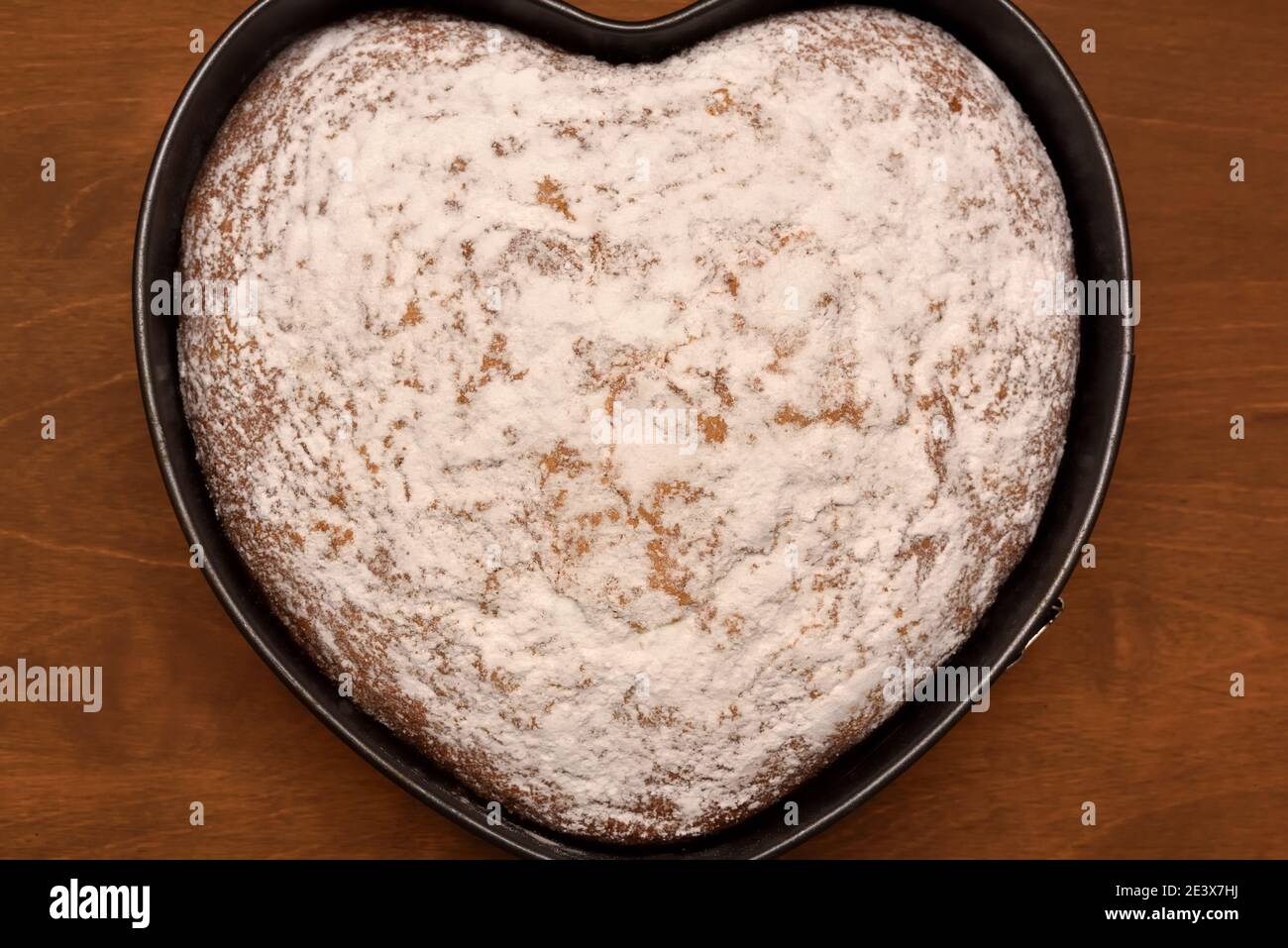 vue de dessus d'un gâteau en forme de coeur avec du sucre en poudre, fraîchement cuit pour des vacances Banque D'Images