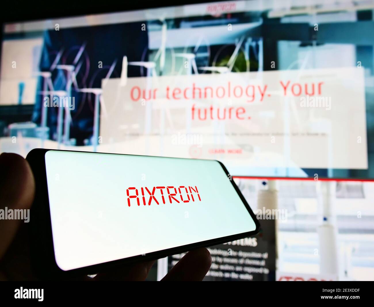 Personne tenant un téléphone portable avec le logo de la société allemande Aixtron se (industrie des semi-conducteurs) exposé. Permet de faire la mise au point au centre-gauche de l'écran du smartphone. Banque D'Images